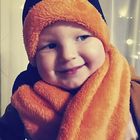 Baby mit orangem Schal und passender Haube